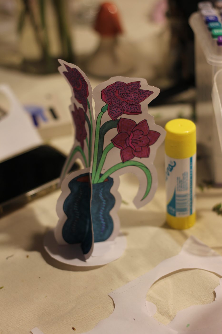 Florero violeta de papel junto a una plasticola