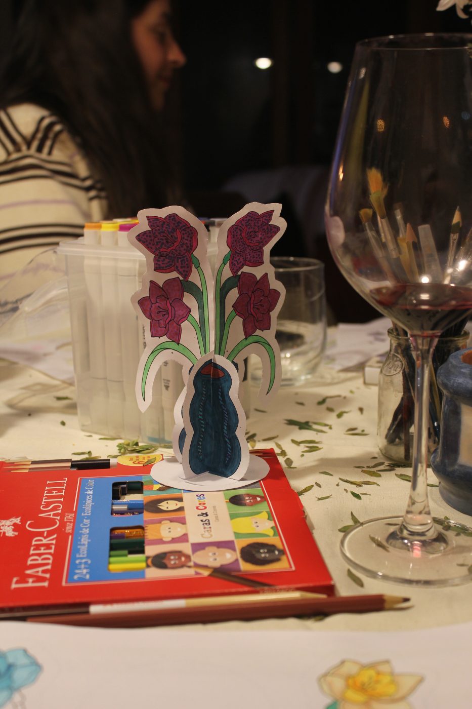Florero de papel junto a una copa de vino